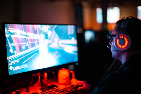 A gamer playing a war zone game in front of his monitor